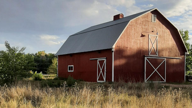 A large red barn set against clouds and grass